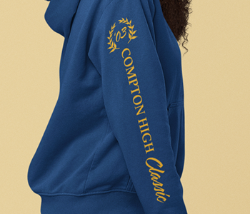 A woman sporting a blue hoodie adorned with gold lettering and unique sleeve and leg designs.